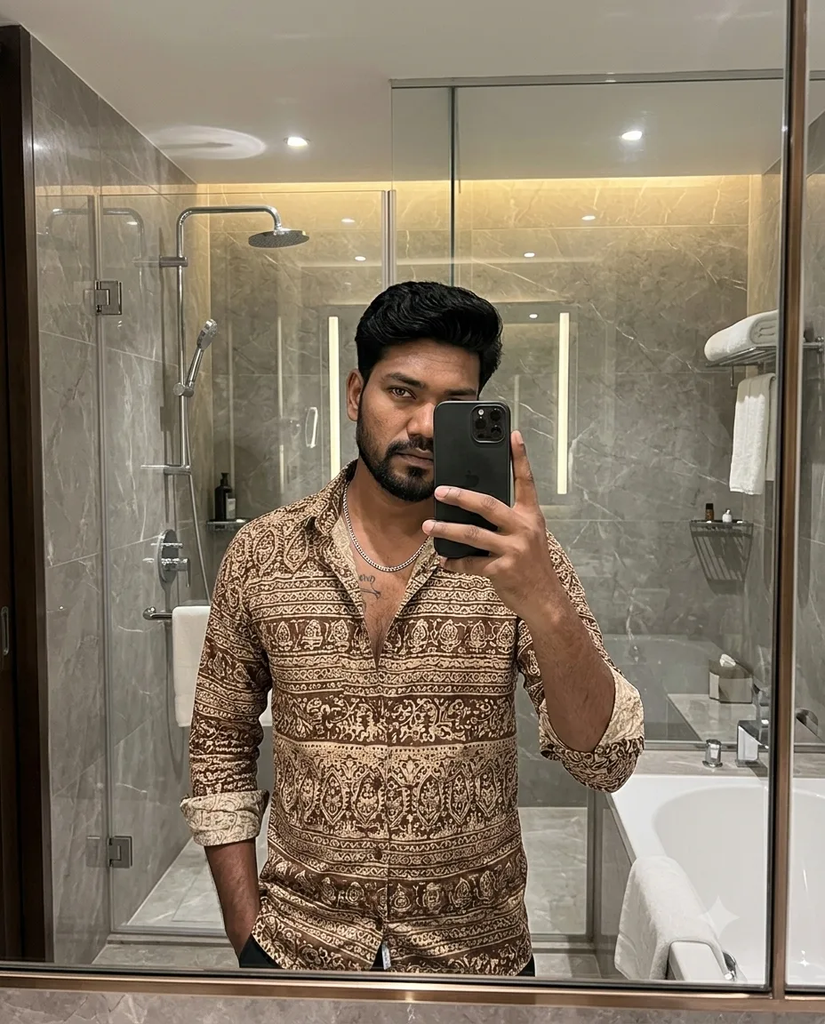 mirror selfie of a young South Asian man standing confidently inside a luxurious modern bathroom