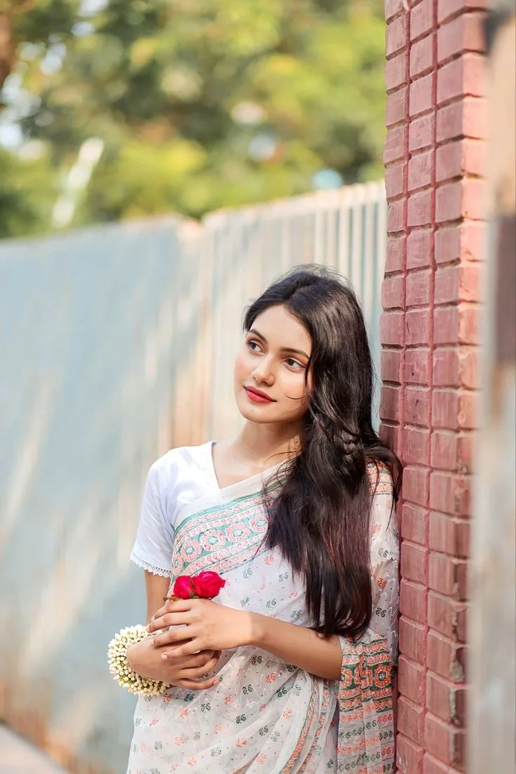 Candid Outdoor Portrait in White Floral Saree by Brick Wall