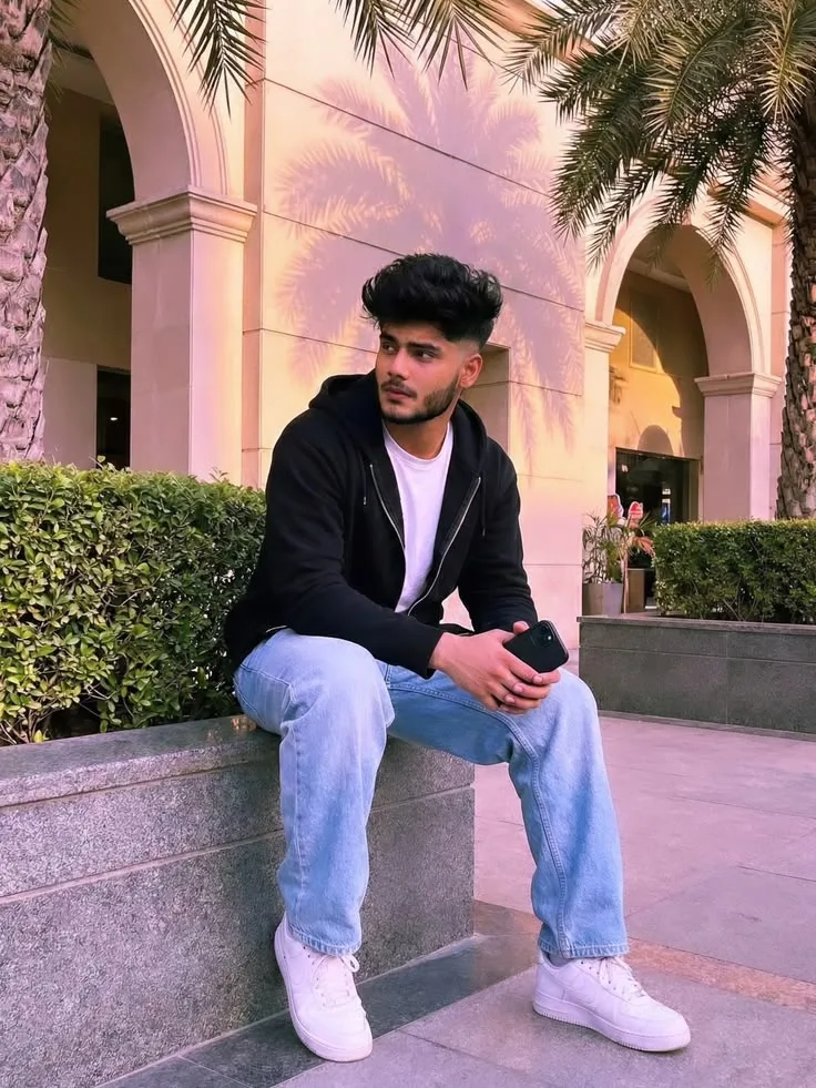 Candid Outdoor Streetwear Portrait of Young Man Seated in Palm Courtyard
