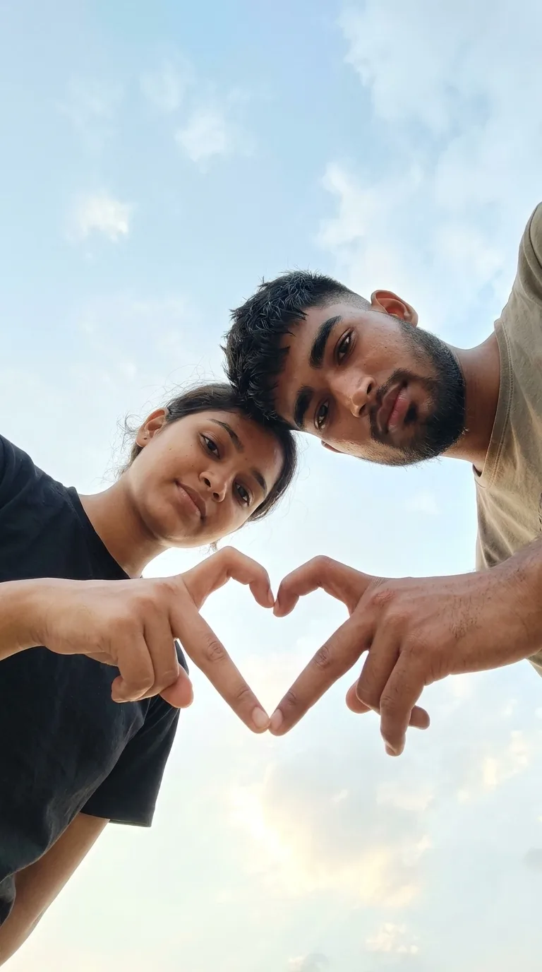 Romantic Couple Low-Angle Hand-Heart Gesture Portrait Under Blue Sky Prompt